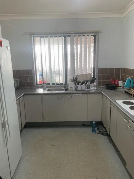 A clean, empty kitchen with white cupboards after a Your Helpers clean